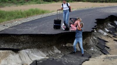 Туристы пытаются пройти по размытой наводнением дороге в районе села Цыбанобалка Краснодарского края, Россия, 14 августа 2021 г. (AP Photo)