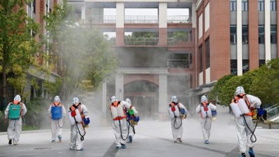Рабочие в защитных костюмах дезинфицируют территорию начальной школы перед началом учебного года в Ухане, провинция Хубэй, Китай, 25 августа 2021 г.