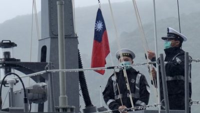 Двое военнослужащих ВМС Тайваня поднимают государственный флаг во время официальной церемонии на верфи в Суао, городке в восточном тайваньском уезде Илань, 15 декабря 2020 г.