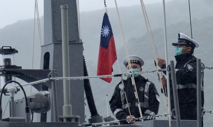 Двое военнослужащих ВМС Тайваня поднимают государственный флаг во время официальной церемонии на верфи в Суао, городке в восточном тайваньском уезде Илань, 15 декабря 2020 г.