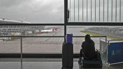 Пассажирка сидит на своём багаже после отмены всех рейсов в международном аэропорту Пудун в Шанхае, Китай