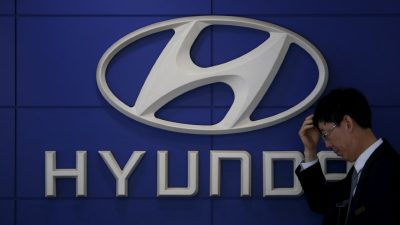 Продавец автомобилей стоит перед логотипом компании Hyundai Motor в дилерском центре в Сеуле, Южная Корея, 25 апреля 2016 года. (Kim Hong-Ji/File Photo/Reuters)