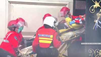 Сотрудники службы экстренной помощи выносят человека на носилках из здания в Гонконге, 8 октября 2012 г. Screenshot via NTD/TVB via Reuters