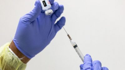 Медицинский волонтёр готовит вакцинацию против коронавируса Moderna для пациента в бесплатной клинике Lestonnac в Ориндж, штат Калифорния