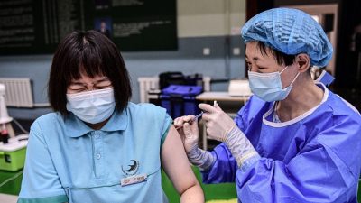 Реакция студентки на получение вакцины против Covid-19 от Sinopharm в лицее Шеньяна китайской провинции Ляонин (северо-запад), 28 июля 2021 г. (China OUT STR/AFP via Getty Images) 