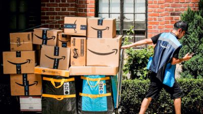 Сотрудник службы доставки Amazon тянет тележку, полную посылок, во время ежегодной акции Prime Day в Нью-Йорке, 21 июня 2021 г. (Brendan McDermid/Reuters)