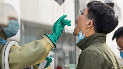 Медицинский работник берёт мазок на COVID-19 на станции тестирования в Пекине, Китай, 25 октября 2021 г. (Noel Celis/AFP via Getty Images)