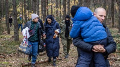 Сирийские беженцы с пограничниками в лесу недалеко от Клещеле, Польша, 22 октября 2021 г. (Photo by WOJTEK RADWANSKI/AFP via Getty Images)