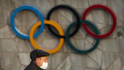 Мужчина на фоне олимпийских колец предстоящих зимних Олимпийских игр 2022 года в Пекине, 2 февраля 2021 года. (Mark Schiefelbein/AP Photo)