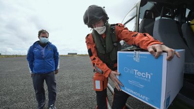 Доктор Алекс Мишель принимает вакцины COVID-19 от члена экипажа ирландского авиационного корпуса, когда военные помогают проводить вакцинацию на отдалённых островах в Инишбофине, Ирландия, 18 мая 2021 года. (Charles McQuillan/Getty Images)