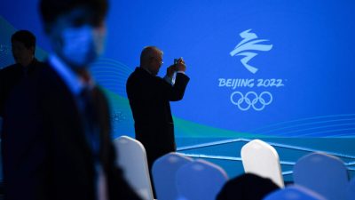 Мужчина фотографирует логотип зимних Олимпийских игр 2022 года в Пекине во время мероприятия «100 дней обратного отсчёта» Паралимпийских зимних игр 2022 года в Национальном водном центре в Пекине, 24 ноября 2021 года. (Wang Zhao/AFP via Getty Images)