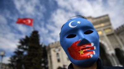Демонстрант в маске, раскрашенной в цвета флага Восточного Туркестана, принимает участие в акции протеста сторонников уйгурского меньшинства 1 апреля 2021 года на площади Бязид в Стамбуле. (Ozan Kose/AFP via Getty Images)