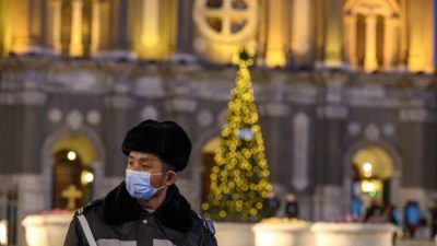 Охранник в маске на страже церкви Святого Иосифа во время мессы в канун Рождества в Пекине 24 декабря 2020 г. (Noel Cells/AFP via Getty Images)