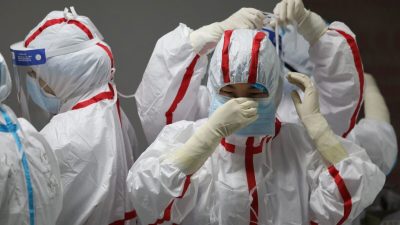 Медицинский персонал надевает защитное снаряжение перед осмотром пациентов с коронавирусом COVID-19 в больнице Красного Креста в Ухане, Китай, 16 марта 2020 года. Фото: STR/AFP via Getty Images
