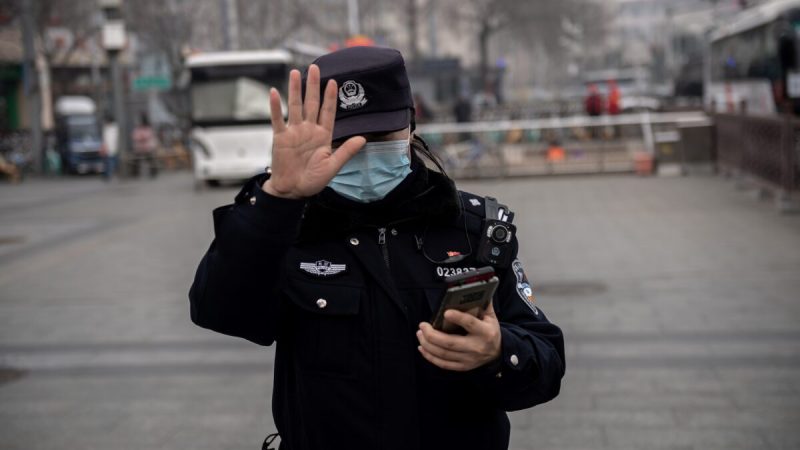 Полицейский жестом просит журналиста не фотографировать в Пекине, Китай, 5 марта 2021 года. (NICOLAS ASFOURI/AFP via Getty Images) 