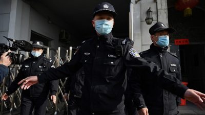 Полицейские охраняют боковой вход после прибытия полицейских машин в Народный суд промежуточной инстанции Даньдун в северо-восточной провинции Китая Ляонин 19 марта 2021 г. Фото: Noel Celis/AFP via Getty Images

