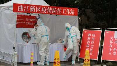Государственные служащие в защитной одежде собираются на рабочем месте для борьбы с пандемией возле жилого квартала в городе Сиань на северо-западе Китая, провинция Шэньси, 3 января 2022 года. (Chinatopix Via AP)