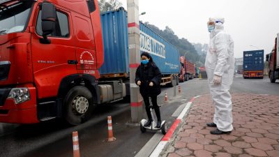 Вьетнамский медицинский работник осматривает контейнеровозы, следующие из Китая во Вьетнам, у пограничных ворот Хуу Нги, соединяющих с Китаем, в провинции Лангшон, Вьетнам, 20 февраля 2020 г. Фото: Kham / Reuters
