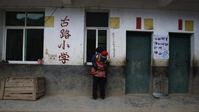 Пожилая женщина из народности И наблюдает за учащимися на уроке в школе в деревне Гулукан 17 ноября 2008 года в уезде Ханьюань, провинция Сычуань, Китай. Фото: Guang Niu/Getty Images
