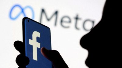 Женщина держит смартфон с логотипом Facebook перед изображением нового ребрендингового логотипа Facebook Мета, 28 октября 2021 года. Фото: Dado Ruvic/Illustration/Reuters