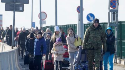 Польский пограничник помогает беженцам из Украины, прибывающим в Польшу, на пограничном переходе Корчова, Польша, 26 февраля 2022 года. (Czarek Sokolowski/AP Photo)