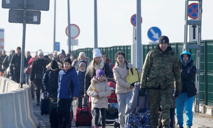 Польский пограничник помогает беженцам из Украины, прибывающим в Польшу, на пограничном переходе Корчова, Польша, 26 февраля 2022 года. (Czarek Sokolowski/AP Photo)