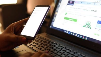 Женщина использует смартфон перед ноутбуком в Абиджане, 3 апреля 2019 г. Фото: SSOUF SANOGO/AFP via Getty Images
