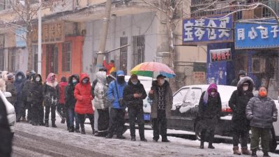 Люди стоят в очереди на анализ COVID-19 во время снегопада в Харбине в провинции Хэйлунцзян 2 марта 2022 года. (STR/AFP via Getty Images)
