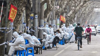 Рабочие в защитной одежде рядом с некоторыми зонами блокировки после обнаружения новых случаев заболевания COVID-19 в Шанхае 14 марта 2022 года. (HectorRetamal/AFP viaGettyImages)
