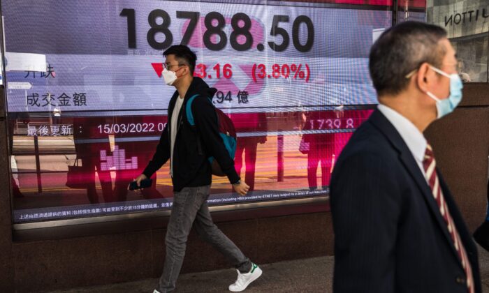 Мужчина проходит мимо дисплея с индексом Hang Seng в Гонконге, 15 марта 2022 года. Фото: (Dale de la Rey/AFP via Getty Images
