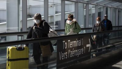 Люди выходят из терминала после прибытия в международный аэропорт Пирсон в Торонто 16 марта 2020 года. (The Canadian Press/Nathan Denette)
