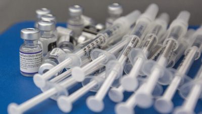 Шприцы и флаконы с вакциной COVID-19 компании Pfizer-BioNTech на рабочей поверхности во время работы клиники в колледже Святого Лаврентия в Кингстоне, Онталия, 18 декабря 2021 года. (The Canadian Press/Lars Hagberg)

