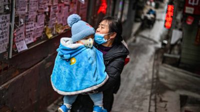 Женщина в маске с ребёнком на руках в Ухане, провинция Хубэй в центральной части Китая, 22 января 2021 года. (Hector Retamal/AFP via Getty Images)
