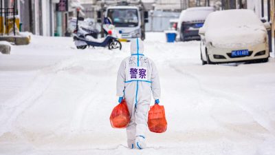 Полицейский в средствах индивидуальной защиты (СИЗ) несёт продукты питания и повседневные принадлежности, которые будут раздаваться жителям в зоне ограниченного проживания в связи с распространением коронавируса COVID-19 в Маньчжоули в китайском регионе Северная Внутренняя Монголия 15 марта 2022 года. (STR/AFP via Getty Images) 