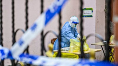 Медицинский работник просматривает пакет в комплексе, когда жители проходят тестирование на COVID-19 в комплексе в районе Цзинъань в Шанхае 29 марта 2022 года. (Hector Retamal/AFP via Getty Images)
