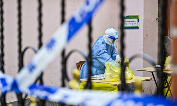 Жители Шанхая не могут купить продукты и лекарства из-за изоляции города Медицинский работник просматривает пакет в комплексе, когда жители проходят тестирование на COVID-19 в комплексе в районе Цзинъань в Шанхае 29 марта 2022 года. (Hector Retamal/AFP via Getty Images)