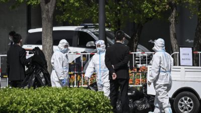 Рабочие в средствах индивидуальной защиты переносят мусор возле офисного комплекса, где недавно были выявлены случаи заболевания COVID-19, в Пекине, 7 апреля 2022 года. (Фото: Jade GAO / AFP) (Фото: JADE GAO/AFP via Getty Images)
