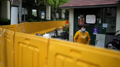 Житель за барьерами, оцепляющими зону карантина в Шанхае 14 апреля 2022 года. (AlySong/Reuters) 