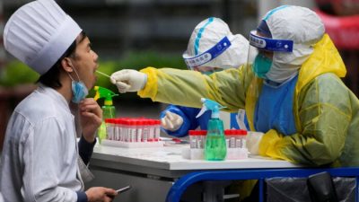 Медицинский работник в защитном костюме берёт образец мазка у кухонного работника для анализа на нуклеиновые кислоты во время блокировки COVID-19 в Шанхае, Китай, 13 мая 2022 года. (Aly Song/Reuters)