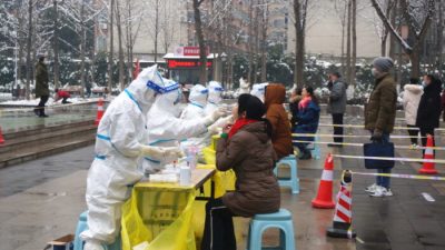 Медицинские работники в защитных костюмах берут мазки у жителей во время общегородского тестирования на нуклеиновые кислоты после случаев заболевания COVID-19 в Чжэнчжоу, провинция Хэнань, Китай, 5 января 2022 года. (CNS photo via Reuters)