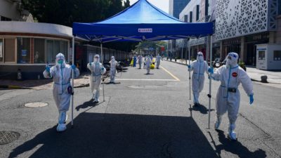 Рабочие в защитных костюмах переносят оборудование для импровизированного участка тестирования на нуклеиновые кислоты в соседний жилой район после завершения проверки на территории комплекса в Шанхае 14 мая 2022 года. (cnsphoto via Reuters)