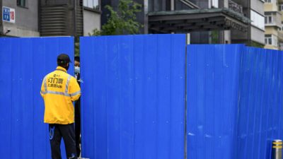 Работник службы доставки беседует с охранником в маске у забаррикадированного входа в жилой комплекс в Пекине 29 апреля 2022 года. (Andy Wong/AP Photo)