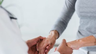  Врач держит за руки пожилого пациента, проверяя признаки и симптомы инсульта. lordn/Adobe Stock