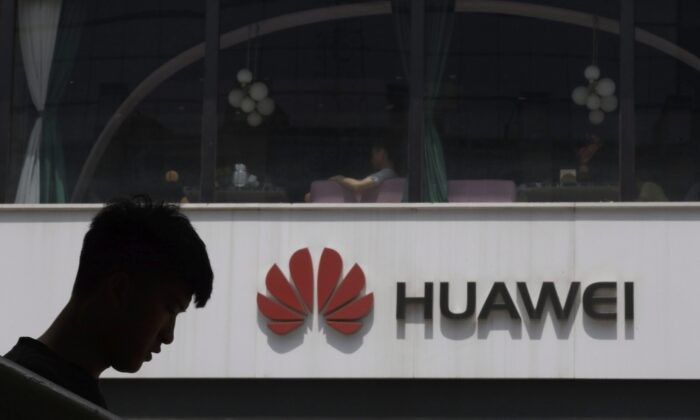 Силуэт китайца рядом с логотипом Huawei в Пекине, 16 мая 2019 года. (AP Photo/Ng Han Guan)
