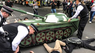 Полиция пытается убрать протестующих, лежащих под макетом танка у посольства Китая во время акции памяти жертв бойни на площади Тяньаньмэнь. Лондон, 4 июня 2022 года. (Peter Simpson/The Epoch Times)