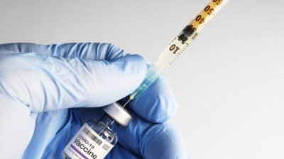 Шприц, вставленный во флакон с вакциной COVID-19. Robert Avgustin/Shutterstock