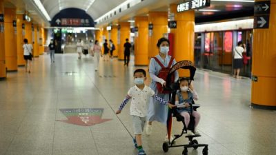 Женщина идёт по станции метро с двумя детьми в Пекине 5 июля 2022 года. (WANG ZHAO/AFP via Getty Images)