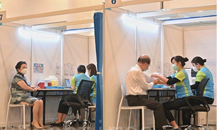 Два местных чиновника прививаются вакциной китайского производства Sinovac от COVID-19. 26 февраля правительство Гонконга начало вакцинацию от COVID-19 для приоритетных групп, включающих людей старше 60 лет. (Song Bilong/The Epoch Times)