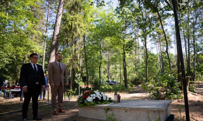 Кароль Навроцкий (справа), глава Института национальной памяти (IPN), стоит перед могилой во время встречи с представителями СМИ недалеко от Дзялдово, Польша, среда, 13 июля 2022 года. (Mikolaj Bujak/Institute of National Remembrance via AP)