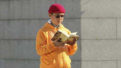 Сяо Цзяньхуа, канадский миллиардер китайского происхождения, читает книгу возле Международного финансового центра в Гонконге в декабре 2013 года. (Next Magazine/AP Photo)
